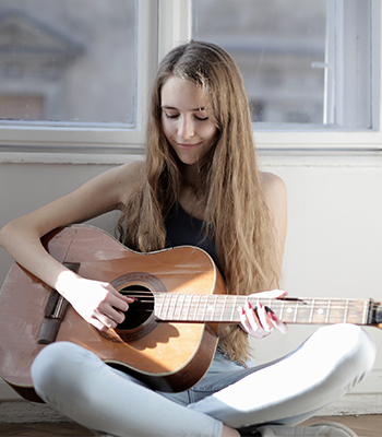 woman practising harmony theory on her guitar